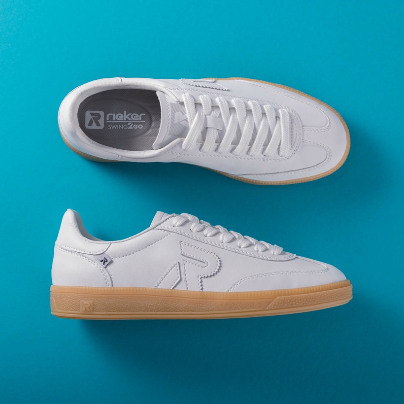 Weiße Rieker Damen Sneaker Low W2200-80 mit Schnürung sowie abriebfester Sohle. Schuhpaar von oben, seitlich auf blauem Hintergrund.
