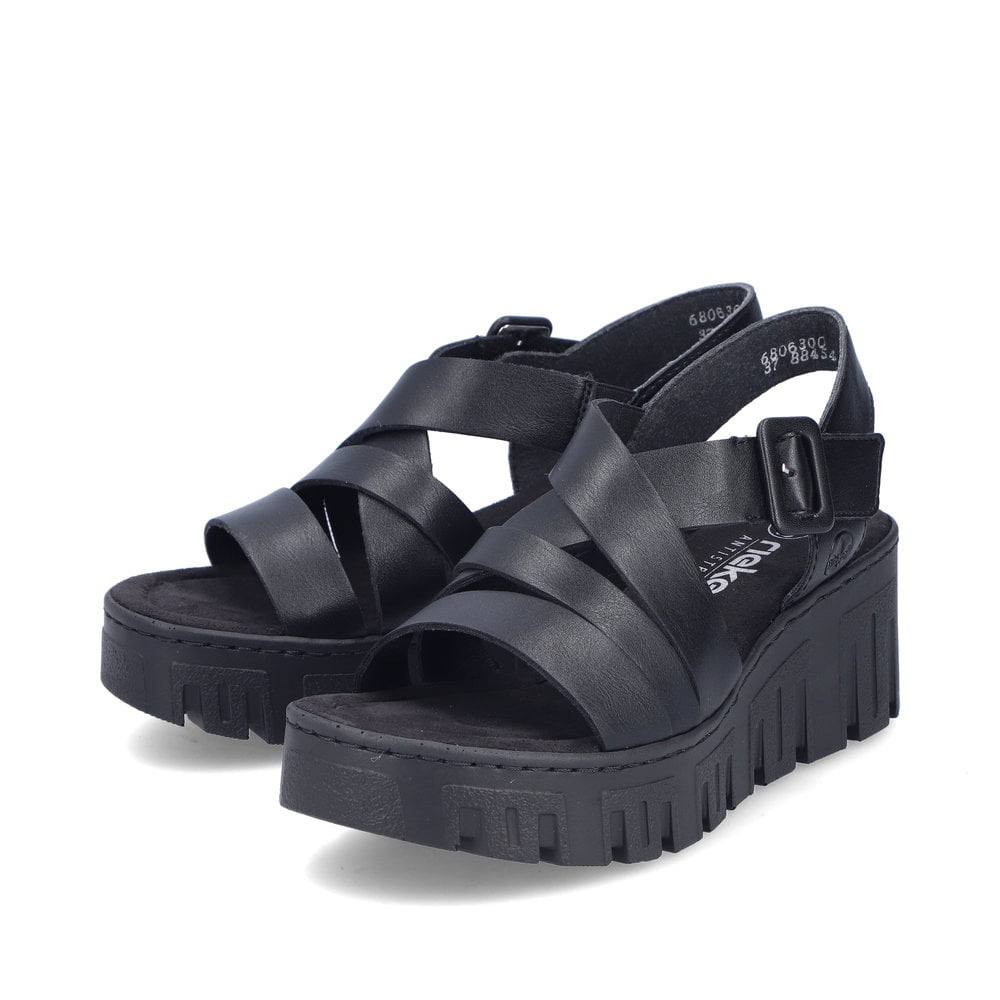Schwarze Rieker Keilsandaletten 68063-00 mit trendiger Schnalle. Schuhpaar seitlich schräg.