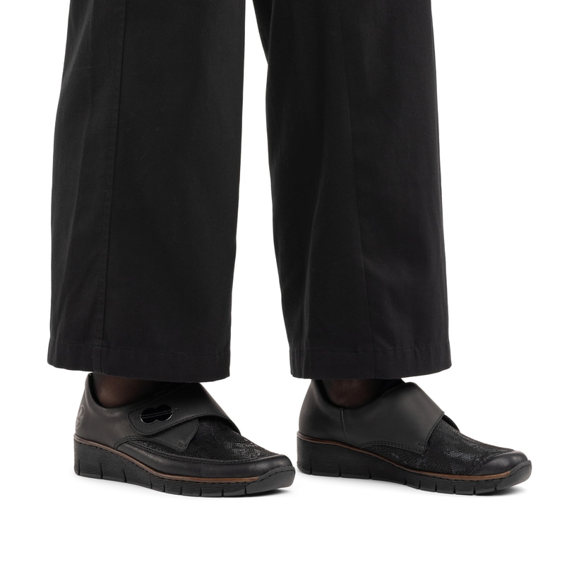 Schwarze Rieker Damen Slipper 537C0-02 mit einem Klettverschluss. Schuh am Fuß.