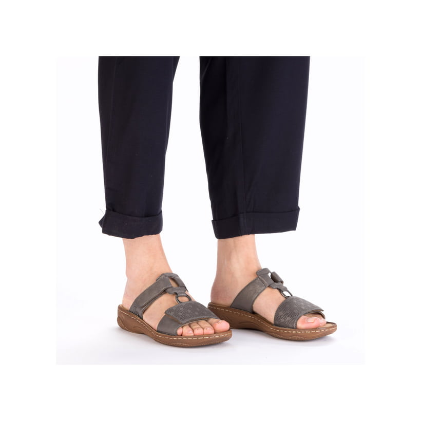 Graue Rieker Damen Pantoletten V2885-42 in Löcheroptik mit einem Klettverschluss. Schuh am Fuß.