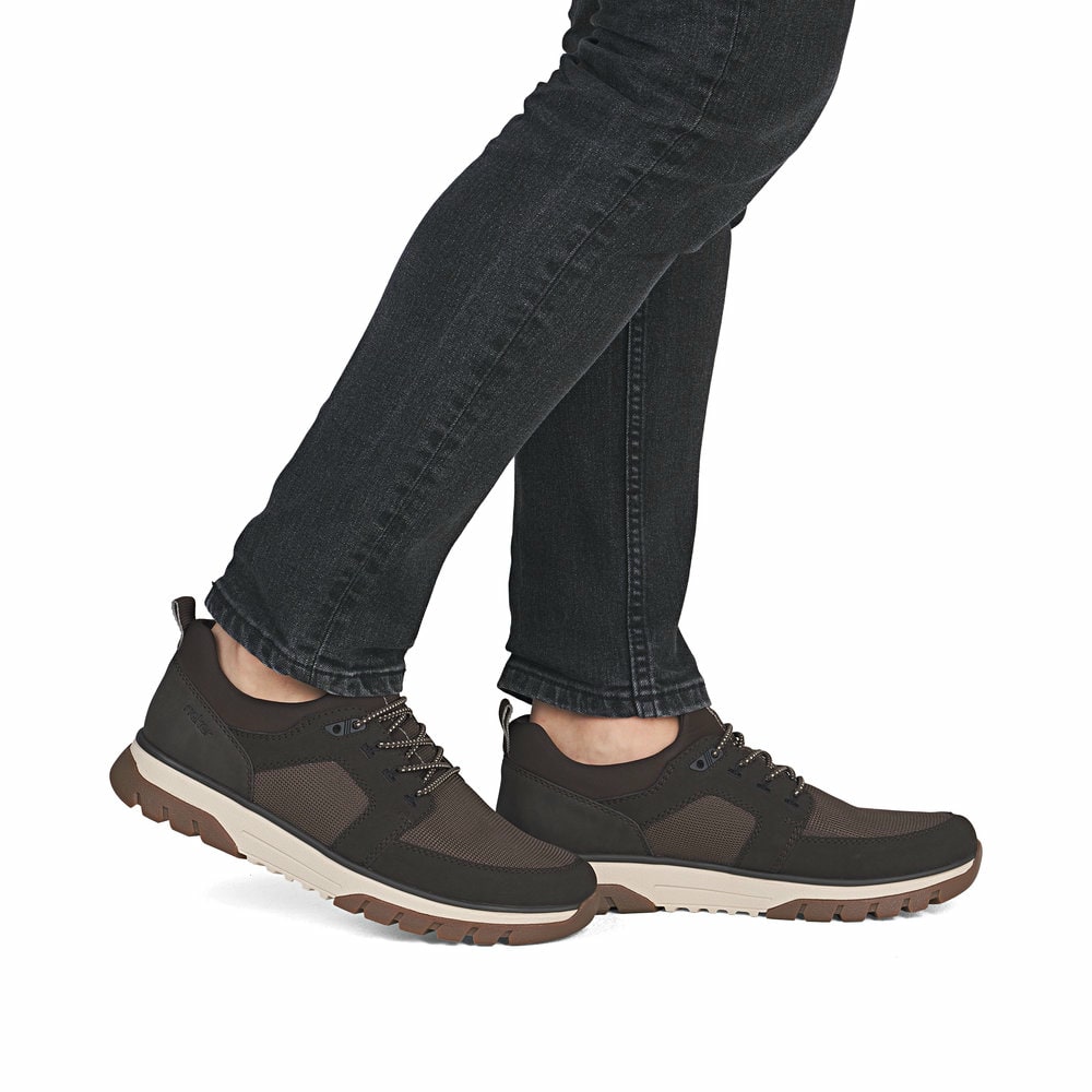 Braune Rieker Herren Slipper B9351-25 mit einem Gummizug sowie der Extraweite H. Schuh am Fuß.