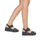 Schwarze vegane Rieker Keilsandaletten 68050-00 mit trendigen Schnalle. Schuh am Fuß.