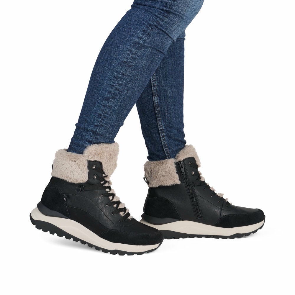 Schwarze Rieker Damen Schnürstiefel W2571-00 mit Reißverschluss sowie Fellkragen. Schuh am Fuß.