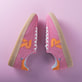 Rosane Rieker Damen Sneaker Low W2200-31 mit Schnürung sowie abriebfester Sohle.  Schuhpaar seitlich gespiegelt auf pinkem Hintergrund.