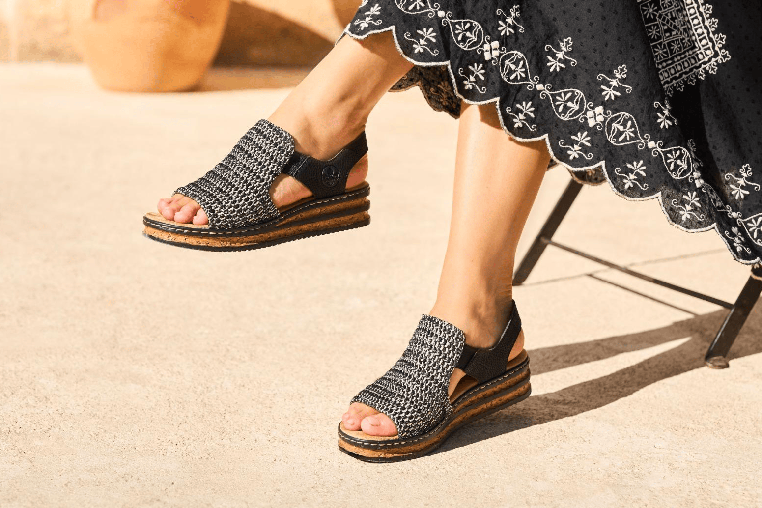 Dame trägt Rieker Keilsandaletten 62971-00 mit Sohle in Korkoptik.