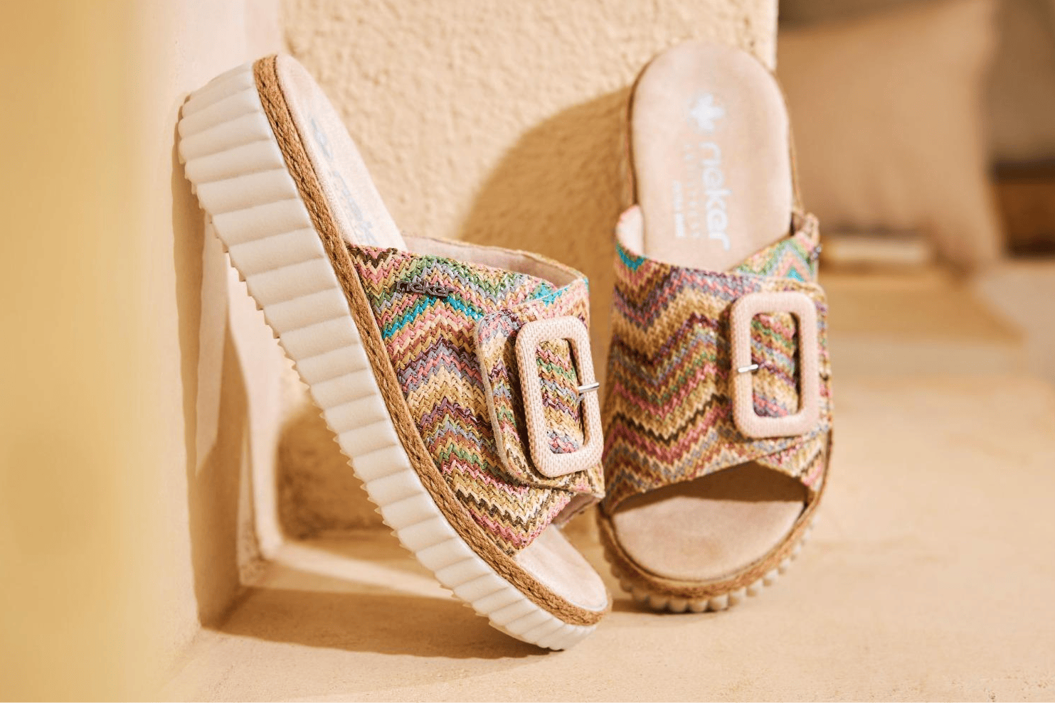 Bunte Rieker Damen Pantoletten 69253-91 lehnen an einer Wand.