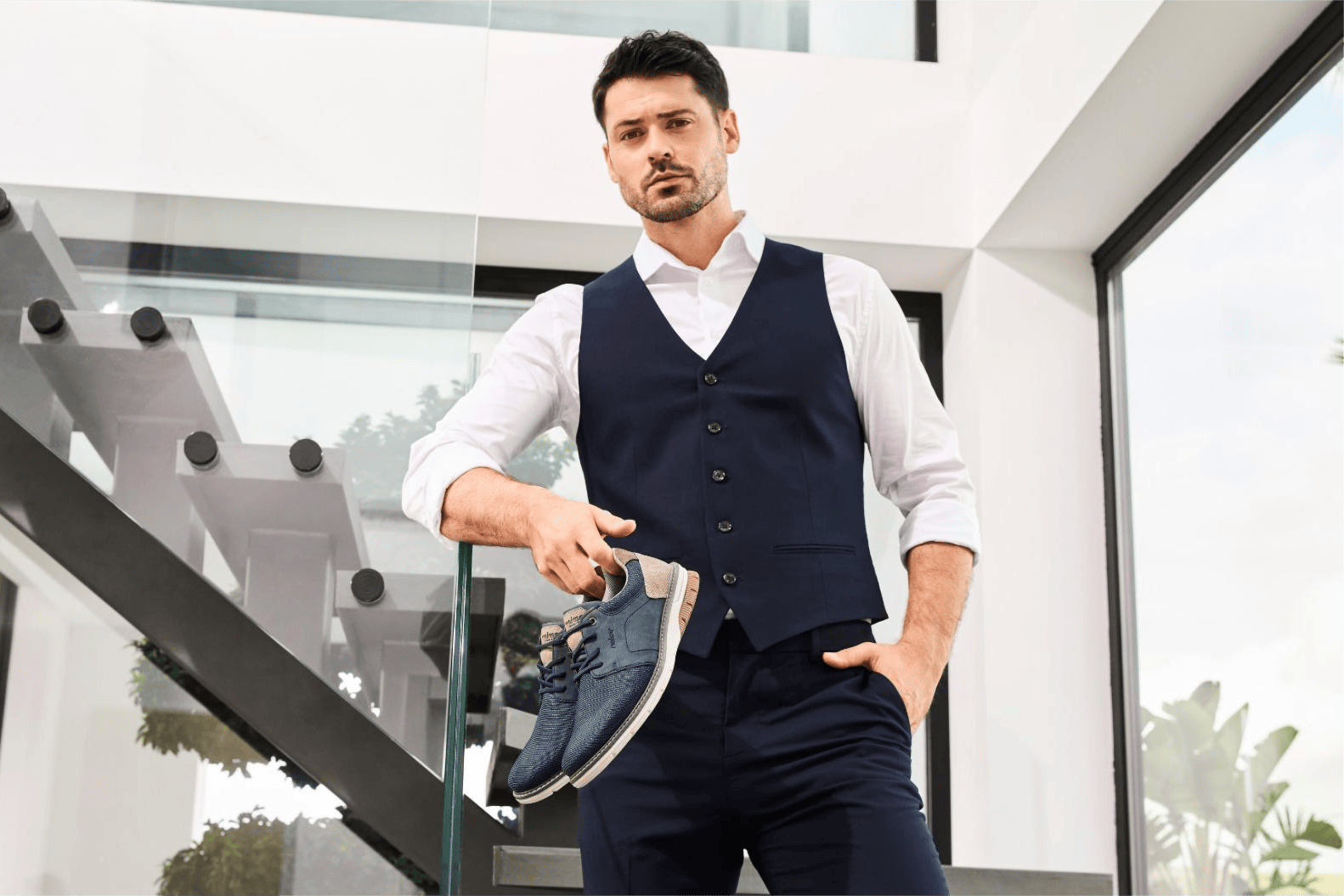 Un homme tient des mocassins élégants 14459-14 de Rieker.