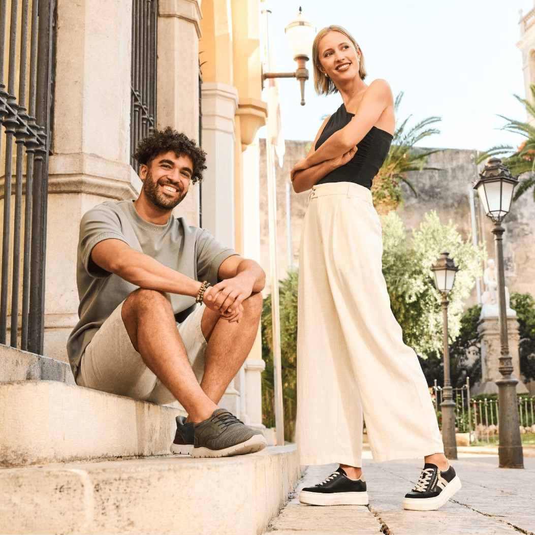 L\'homme est assis et porte des baskets pour homme B6658-52, la femme porte des baskets pour femme M1912-00 de Rieker.