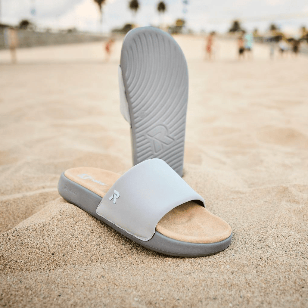 Les slides gris Narooma U3250-40 pour hommes sont enfoncés dans le sable.